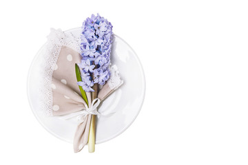 Linen napkin with blue hyacinth on a plate isolated on white