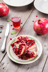 Whole and broken red ripe juicy pomegranates on rustic wooden unpainted table