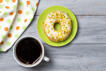 Cup of coffee and pistachios donut on a plate, wooden background