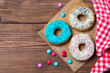 Colorful donuts and smarties on wooden table, top view