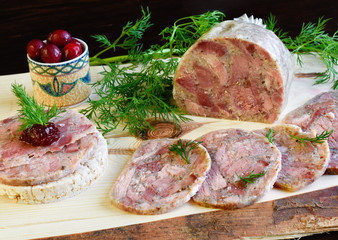 Homemade headcheese with dill and cranberries on a wooden board