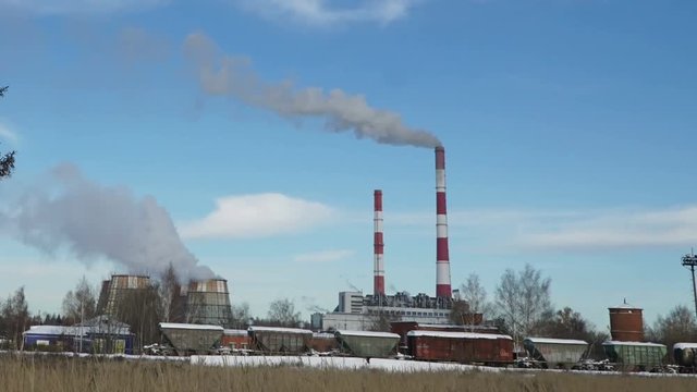 Thermal power plant or a factory with Smoking chimneys and a solitary tree.