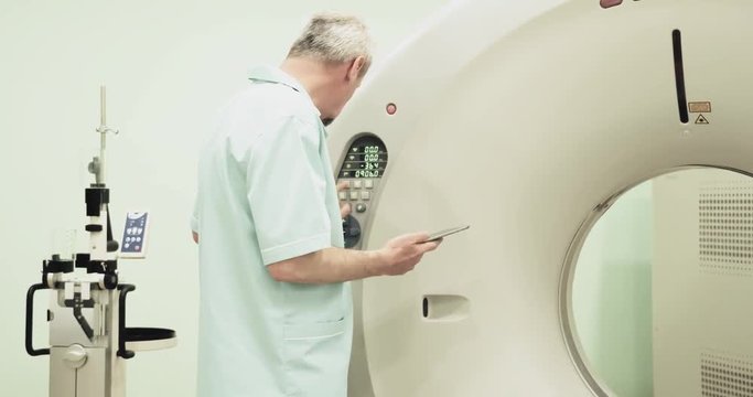 Doctor presses settings button of CT MRI scanner 4k video. Medical equipment: computed tomography machine in diagnostic clinic