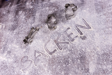 Baking Backen in German letters written in flour on the table