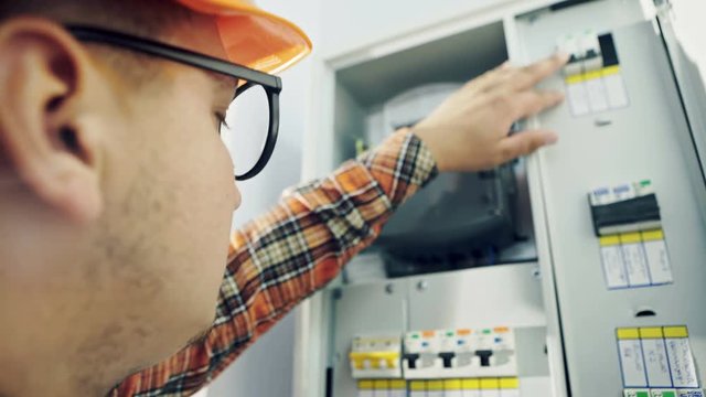 Young adult electrician builder engineer checking equipment in fuse box