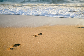 Sunny footprint on the sand and white wave background. swim walk