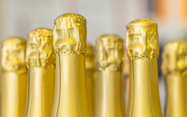 Big amount of golden champagne bottles necks and top caps at standing the light background