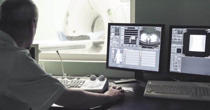 Doctor looking at computer screen while patient in CT MRI scanner 4k video. Computed tomography imaging on monitor