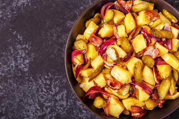 Homemade potato salad with bacon and pickles.