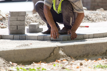 Worker puts sidewalk tile on the road