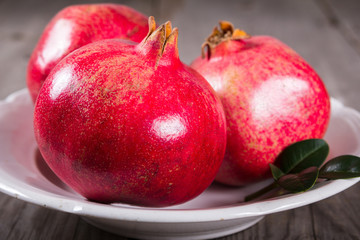Some whole red pomegranate on rustic wooden unpainted table