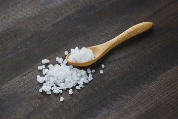 salt crystals on wooden spoon on wooden table