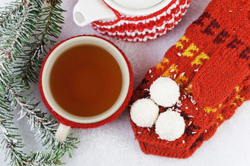 A mug of tea, teapot, mittens, candy