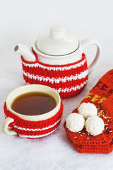 A mug of tea, teapot, mittens, candy