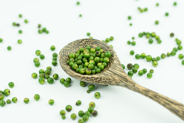 fresh green peppercorns on spoon wood isolated on white