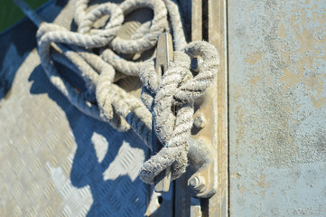 Fototapeta premium Closeup on mooring bollard with rope tied on pier by the sea outdoors background