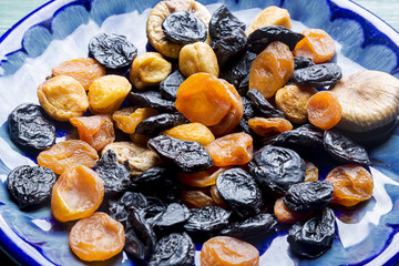 Dried plums and apricots on blue plate