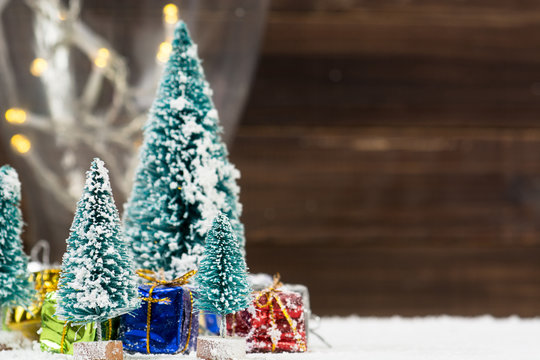Christmas trees with white snow and gift boxes - selective focus
