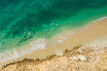 Stark contrast of beautiful turquoise blue ocean meeting yellow beach - obrazy, fototapety, plakaty