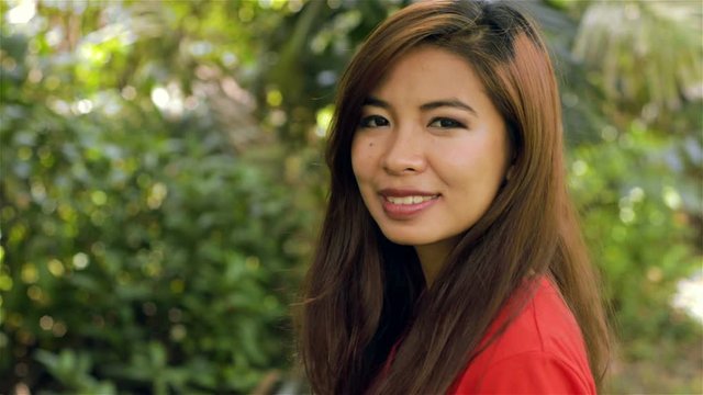 Young Asian woman turning to face the camera and smiling - dolly shot.