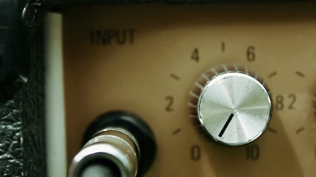 Musician setting the controls on a guitar amp ready to perform