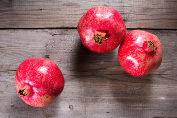 Some whole red pomegranate on rustic wooden unpainted table