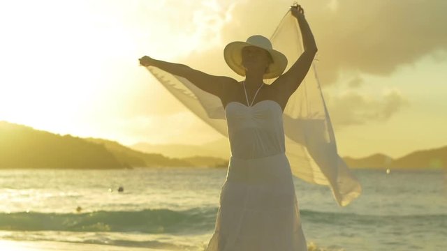 slow motion video of womas twirling sarong on tropical beach at sunset