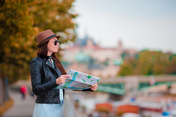 Happy young woman with a city map in city. Travel tourist woman with map outdoors during holidays in Europe.