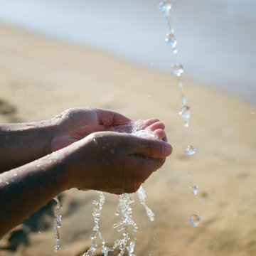 Closeup on hands holding water, sunny beach outdoors background