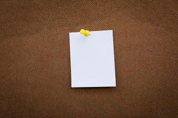 Blank white paper note pinned on cork board with white thumbtack
