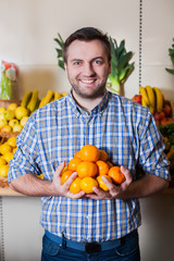 Man holds tangerines in hands.