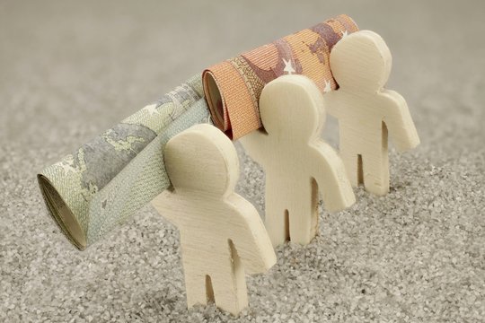 Drei Figuren aus Holz tragen Geldscheine - Nahaufnahme