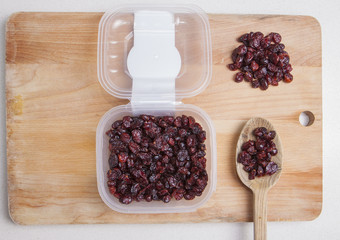 Transparent plastic bowl full of dried blueberry with wooden spo