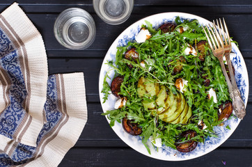Arugula salad with goat cheese and avocado with plums