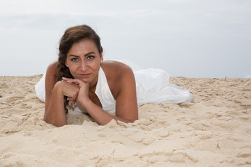Fototapeta na wymiar Pretty bride is lying on the white sand