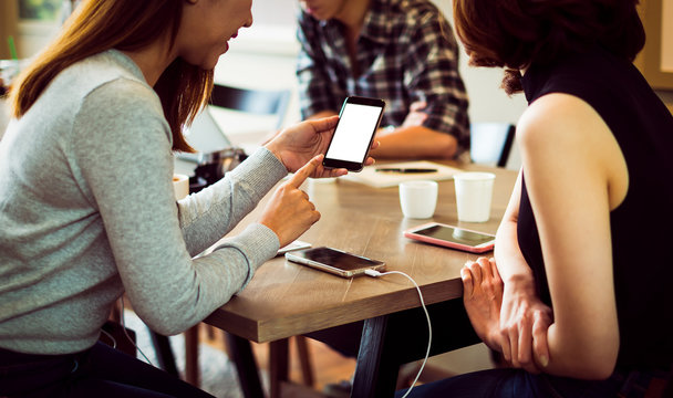 Two Women Having Fun At The Cafe And Looking At Smart Phone. Wom