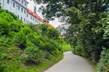 Cloudy day in Prague park, trail between trees and castle
