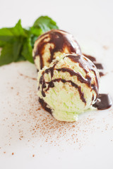 pistachio ice cream with chocolate syrup and mint on a table, selective focus