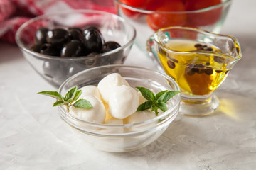 ingredients for salad - cheese, a tomato, olives and oil. selective focus