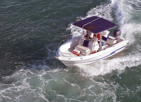 Angled overhead view of a small fishing boat owe red by a single outboard engine