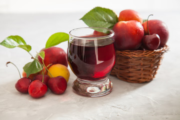 cherry juice in a glass, berries and fruit on a table, selective focus