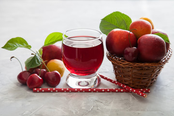 cherry juice in a glass, berries and fruit on a table, selective focus