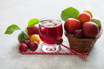 cherry juice in a glass, berries and fruit on a table, selective focus
