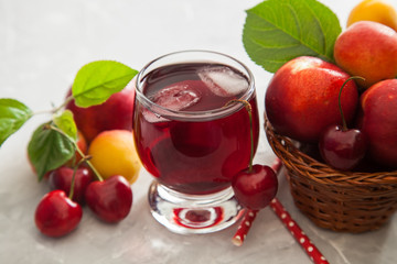 cherry juice in a glass, berries and fruit on a table, selective focus