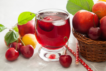 cherry juice in a glass, berries and fruit on a table, selective focus