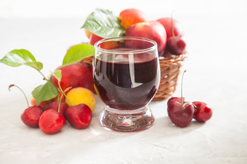cherry juice in a glass, berries and fruit on a table, selective focus