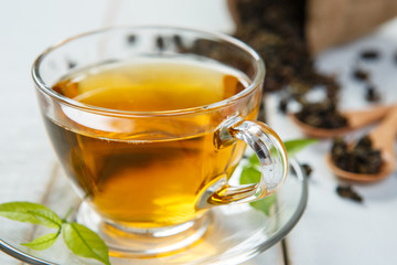 Warm cup of tea and leaves tea on white wooden