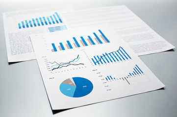 Business reports. Graphs and charts.
Documents on gray reflection background.
