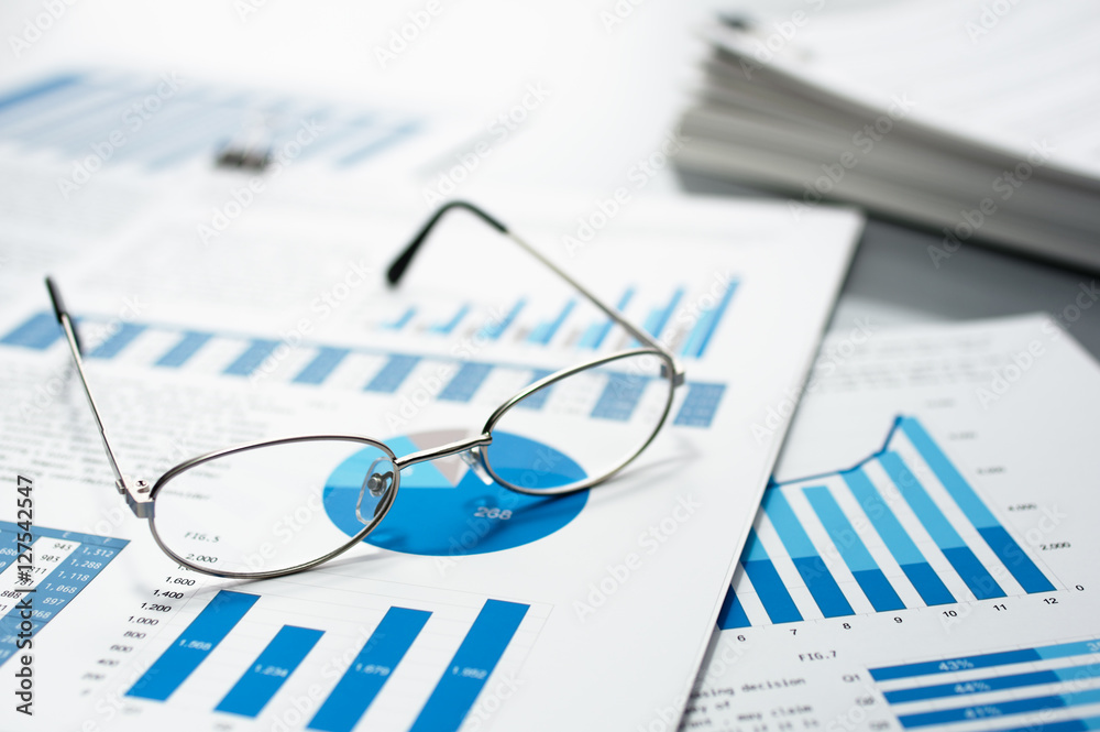 Poster Checking business reports. Glasses and pile of documents.　Many graphs and charts. Pile of documents on gray reflection background.
