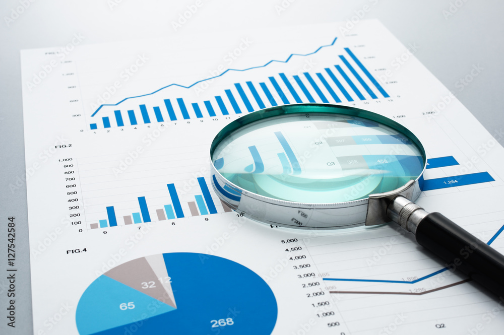 Poster Business document and magnifying glass on gray reflection background.
Many graphs and charts. Concept image of data reviewing.
